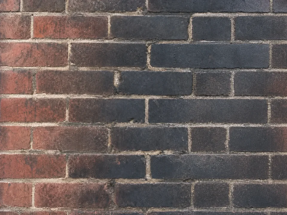 Original soot-stained brick wall with the opening repaired